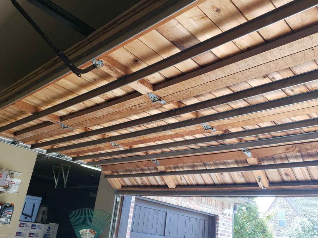 Wooden garage door interior with beams and hardware, showing modern design and structure.