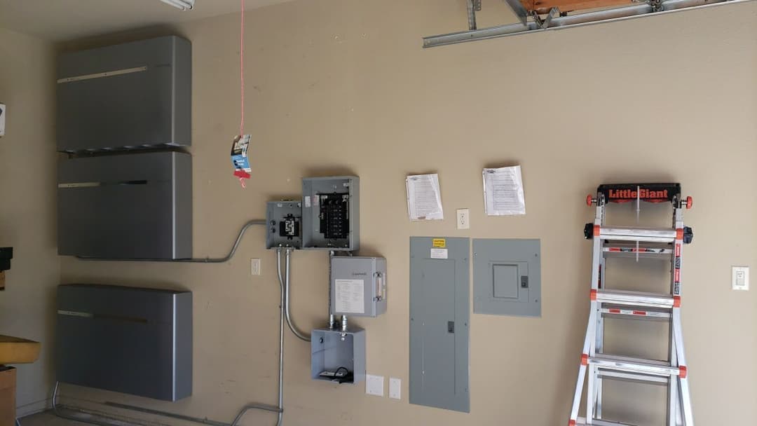 Garage interior with electrical panels, storage cabinets, and a Little Giant ladder.